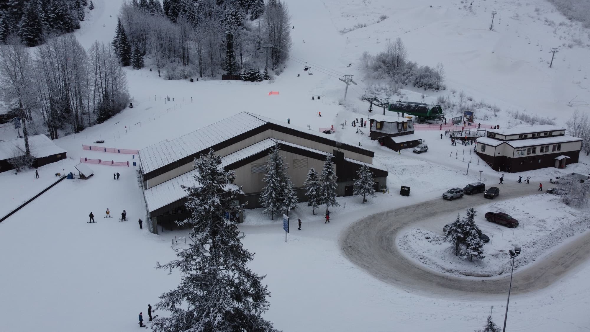 Skiers and chairlifts at the snowy base area of Alyeska Resort seen from above