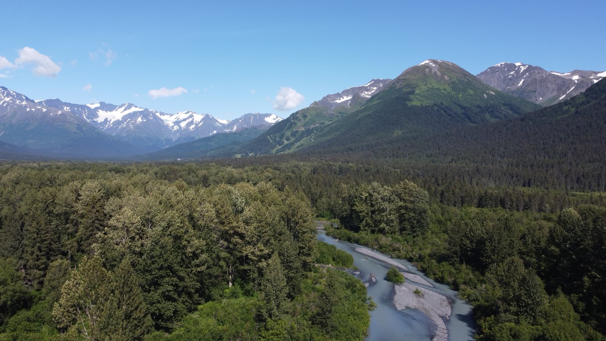 The green Girdwood valley in summer, glacial river winding below snow-streaked Chugach peaks